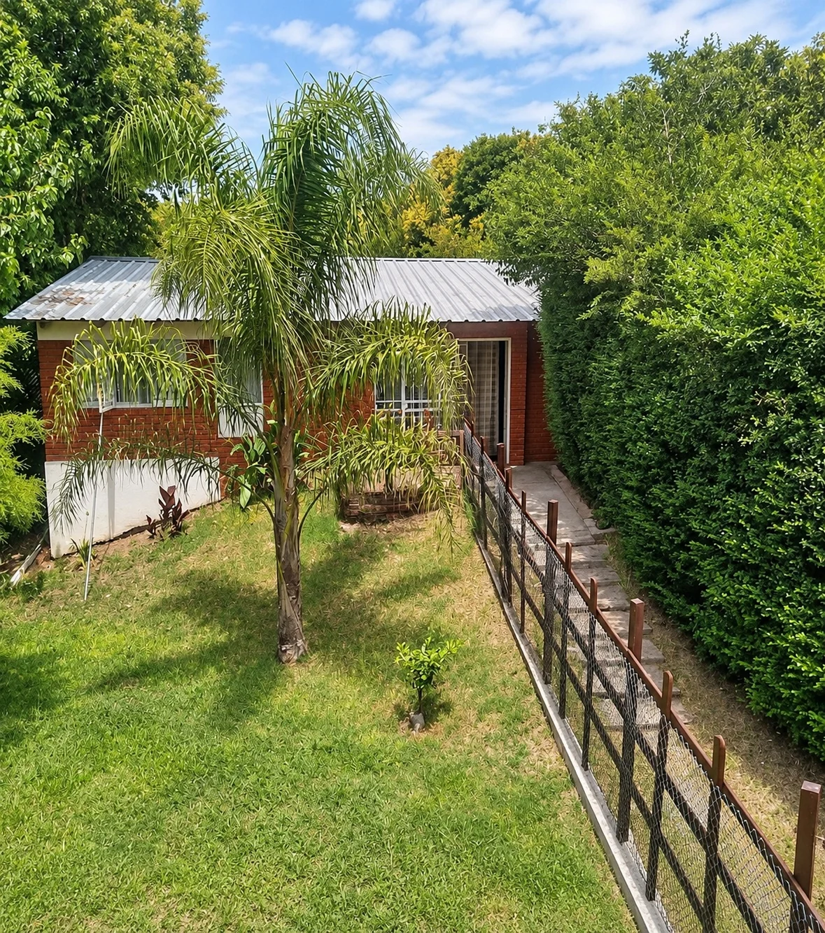 Casa de Campo con palmera y jardín, entre cercos verdes