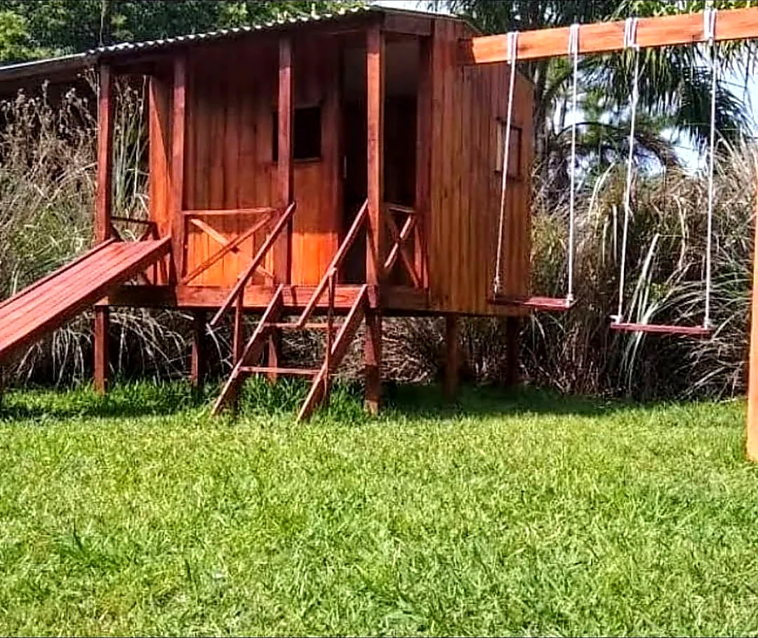 Casita de madera con tobogán y hamacas para chicos