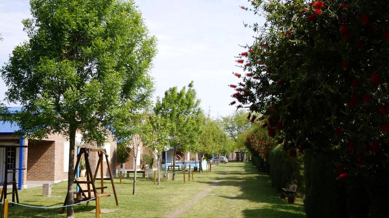 Parque de Cabañas Costa Azul con las cabañas de ladrillo, juegos y arbustos en flor