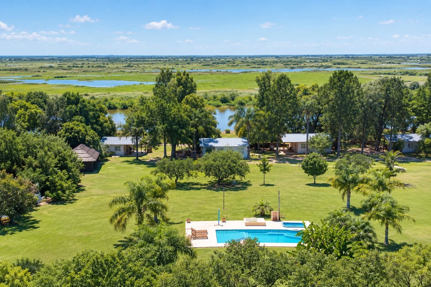 Vista aérea de cabañas, parque y pileta frente al río Coronda