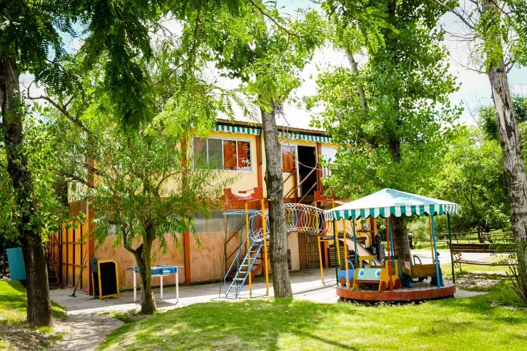Edificio principal entre árboles, con juegos
